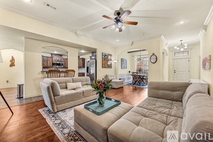 A living room with a beige sofa, a glass coffee table, and a ceiling fan.