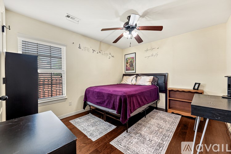 A bedroom with a bed, dresser, and ceiling fan.