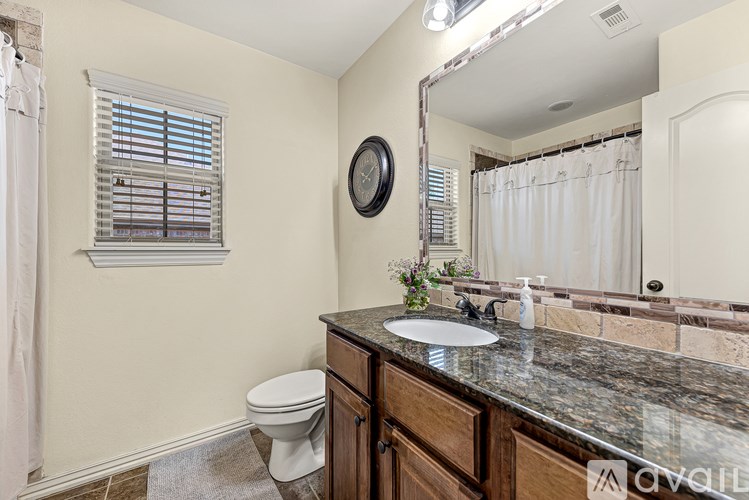 A bathroom with a toilet, sink, and mirror.