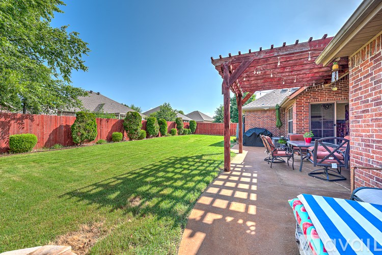 A backyard with a patio and a red fence.
