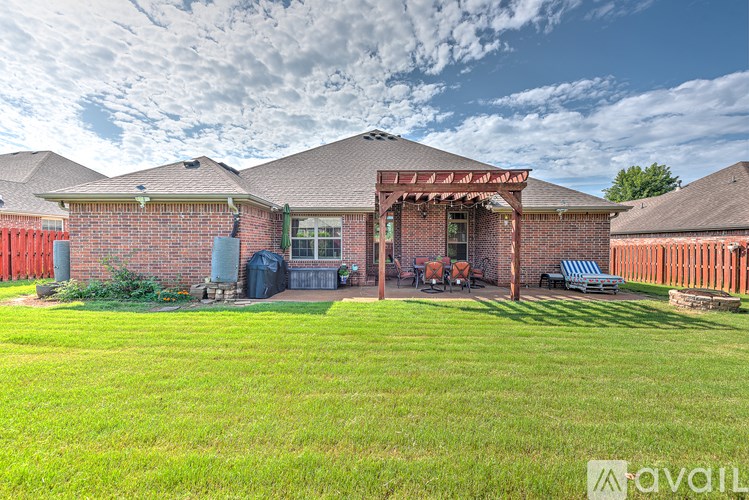 A red brick house with a covered patio and a green lawn.