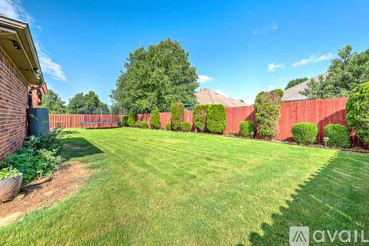 A backyard with a red fence and green grass.