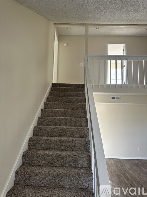 A staircase with a carpeted runner and white railings leads to a second floor.