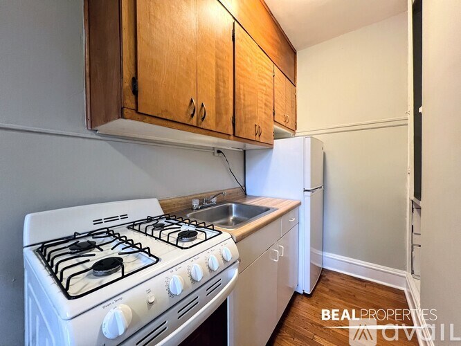 A white gas stove with a white refrigerator and wooden cabinets in a kitchen.