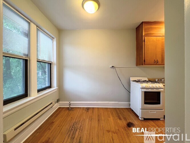 A room with a wood floor, a window, and a wall-mounted oven.