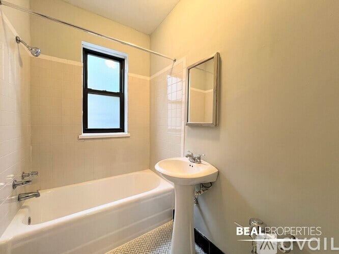 A bathroom with a tub, sink, and mirror.