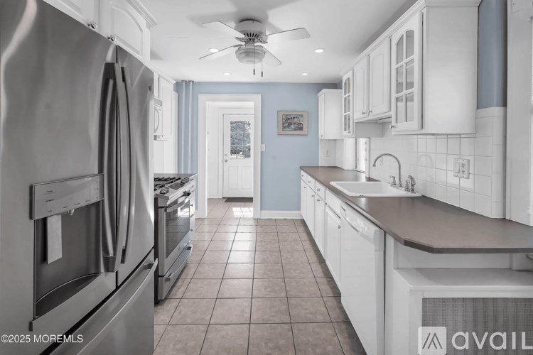 A kitchen with a tile floor and a ceiling fan.