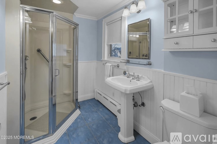 A bathroom with a white sink and a glass shower stall.