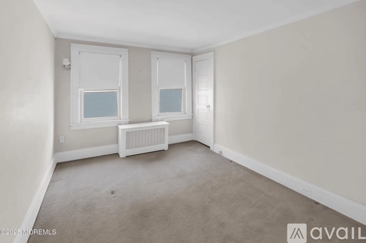 A room with a window, a radiator, and a carpeted floor.