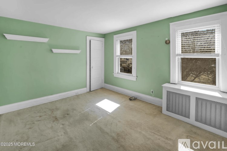 A room with green walls, a window with blinds, and a door.
