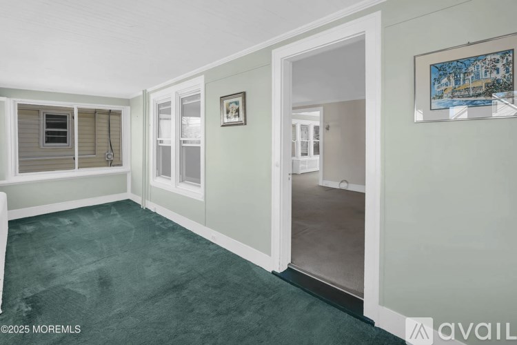 A room with a green floor and white walls, with a painting hanging on the wall.