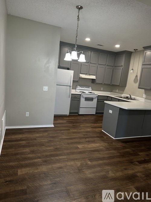 A kitchen with wooden floors and grey cabinets.