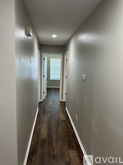 A long hallway with wood floors and white walls.