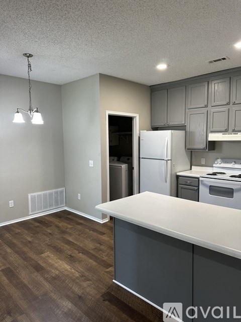 A kitchen with a white counter and a white fridge.