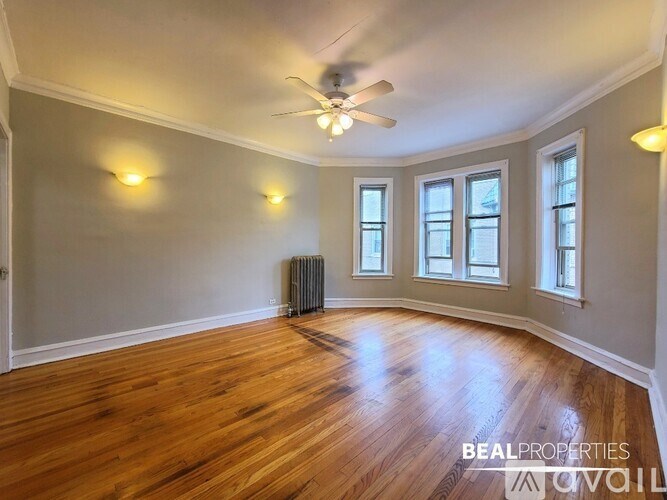 A spacious room with wood flooring and a ceiling fan.