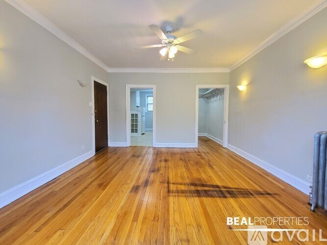 A spacious room with wooden floors and a ceiling fan.