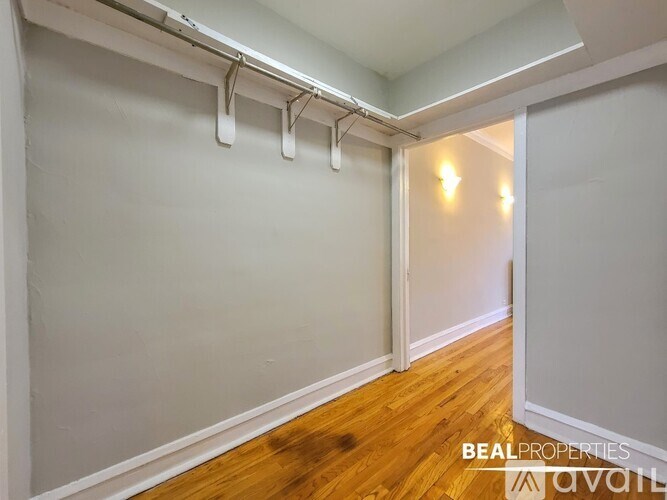 A room with wooden floors and white walls, with a doorway leading to another room.