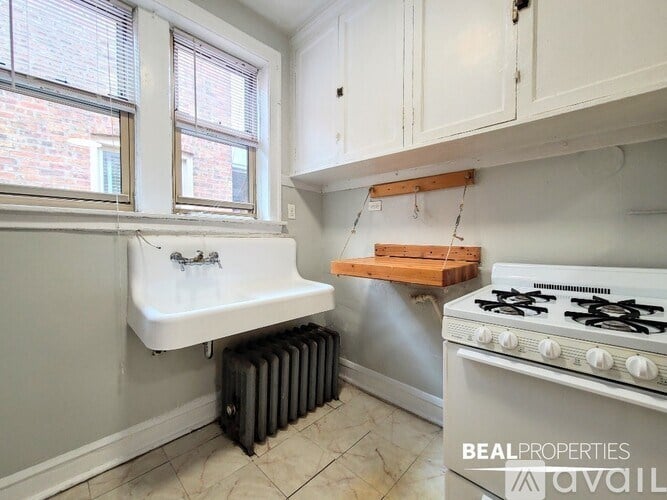 A kitchen with a white stove top oven and a white sink.