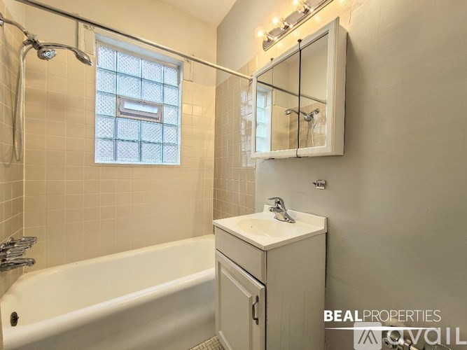 A white bathroom with a tub, sink, and mirror.