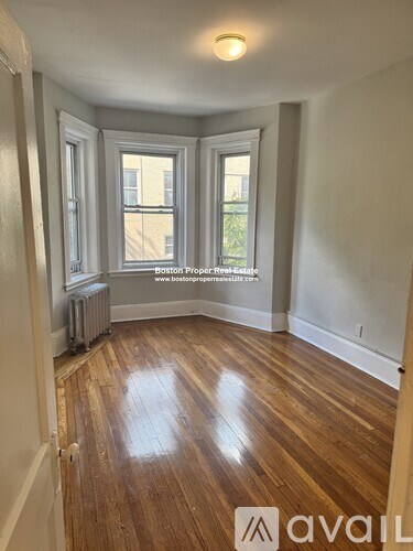 A room with wooden floors and two windows.