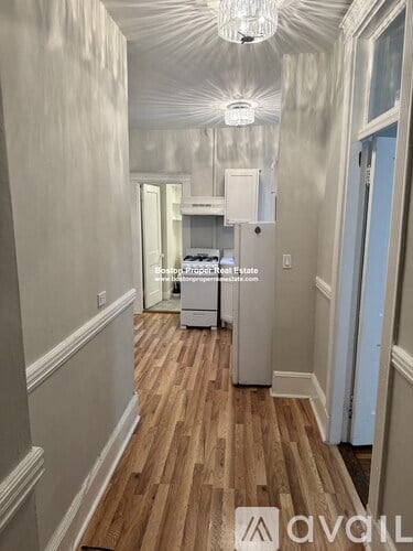 A long hallway with wood floors and white walls.