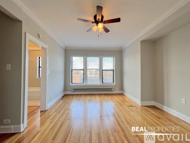 A spacious room with a ceiling fan and wooden flooring.