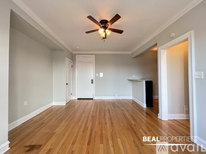 A spacious room with wooden floors and a ceiling fan.