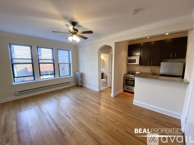 A spacious living room with a kitchen in the background.