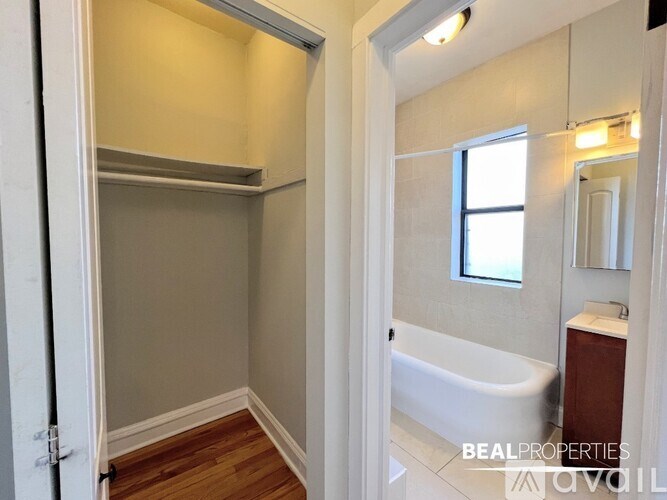 A white bathroom with a tub, sink, and mirror.