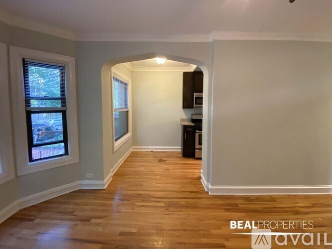 A room with wooden floors and a window overlooking a street.