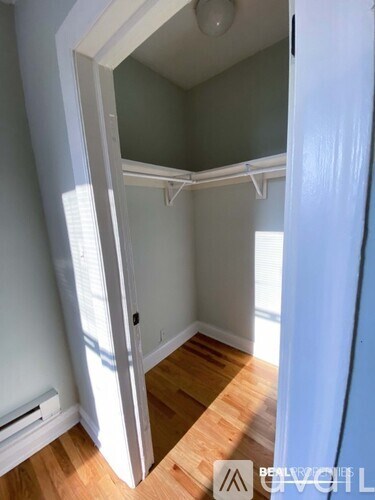 A white door is open to a room with wood flooring.
