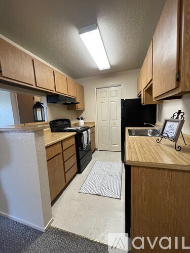 A kitchen with wooden cabinets and a black refrigerator.