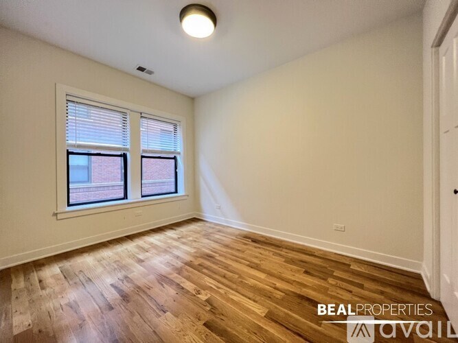 A room with wooden flooring and a window with blinds.