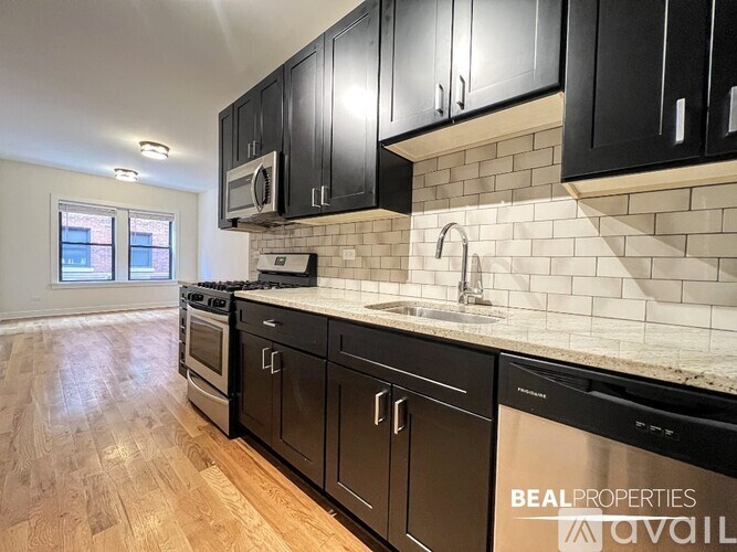 A kitchen with black cabinets and a white tiled backsplash.