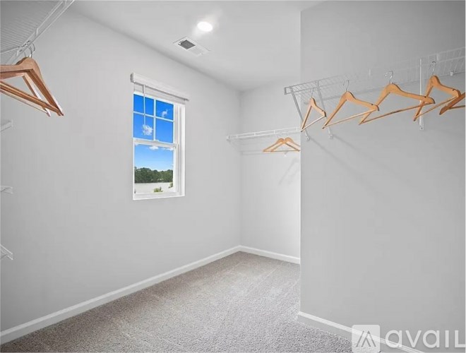 A room with a window and clothes hangers.