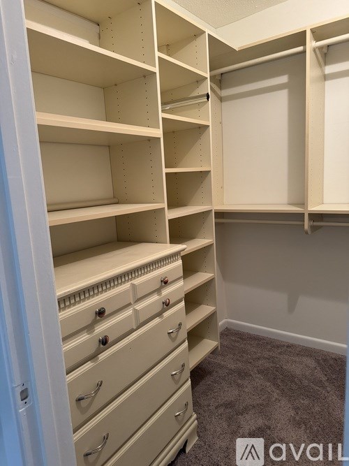 Empty white shelves and drawers in a room.