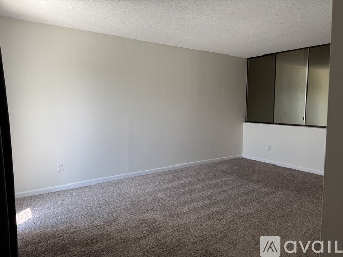 A room with a carpeted floor and a wall-mounted mirror.