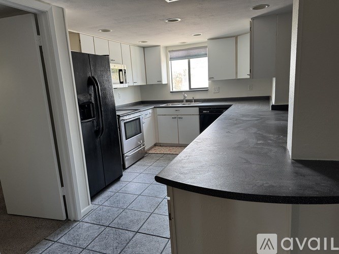 A kitchen with black countertops and white cabinets.