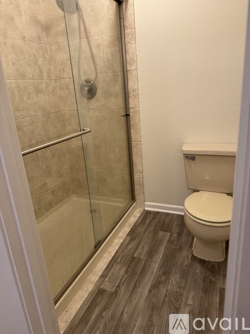 A bathroom with a toilet, glass shower door, and tiled floor.