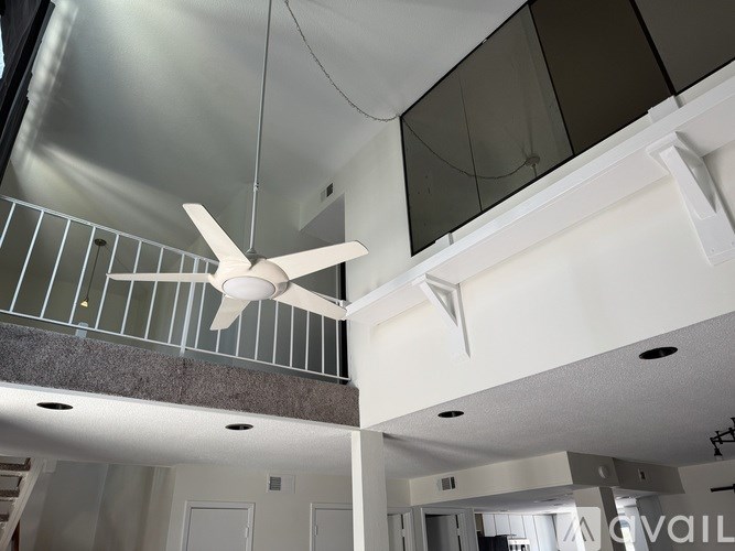 A ceiling fan hangs from the ceiling in a modern, empty room.