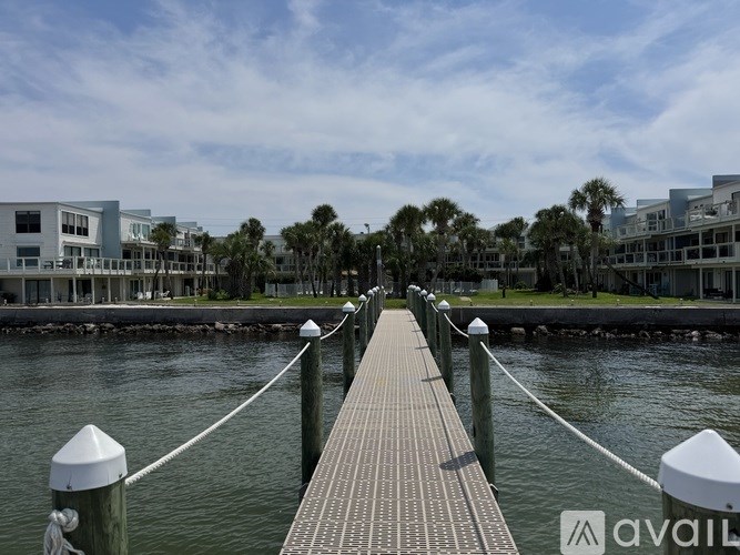 A wooden pier extends into a body of water with buildings in the background.