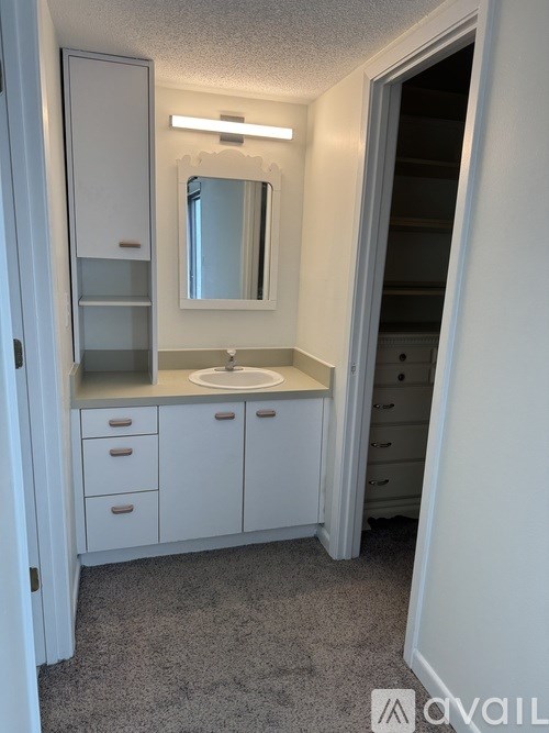 A bathroom with a sink, mirror, and cabinets.