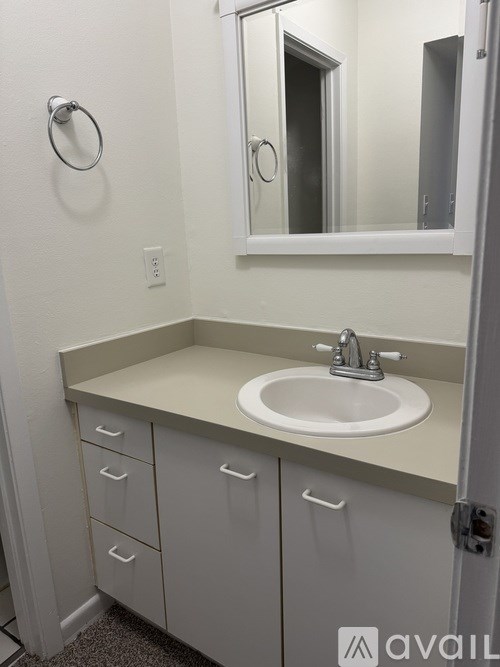 A bathroom with a sink, mirror, and cabinets.
