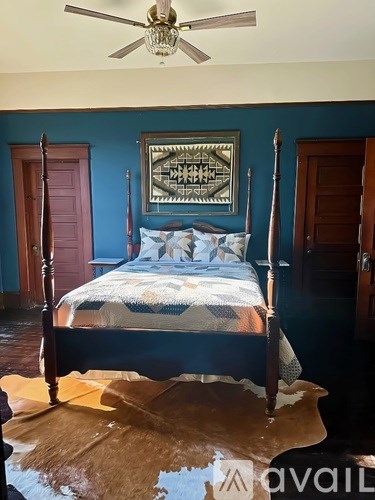 A bedroom with a bed, a ceiling fan, and a rug.