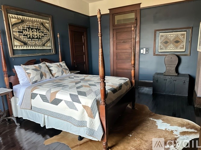 A bed with a wooden frame and a quilt on it is in the center of a room with dark walls.