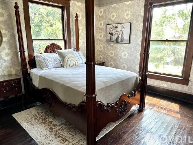 A four poster bed with a white bedspread and pillows.