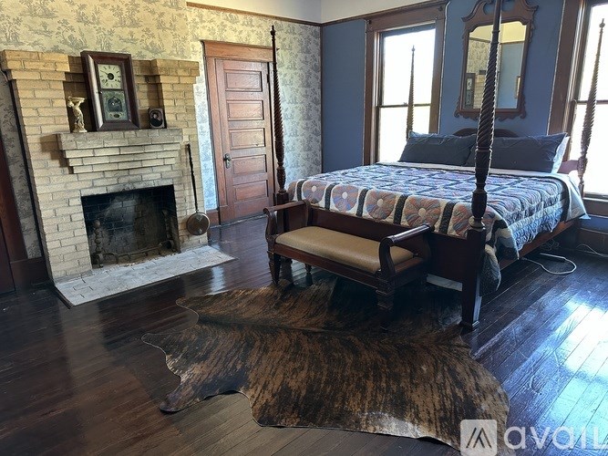 A bedroom with a four poster bed and a fireplace.