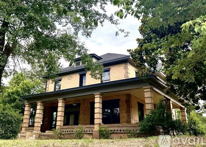 A house with a black roof and a balcony surrounded by trees.