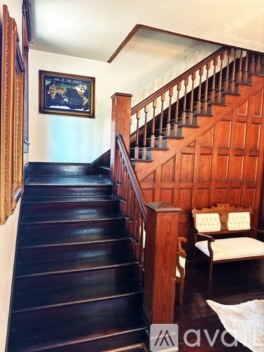 A wooden staircase with a black carpeted floor.