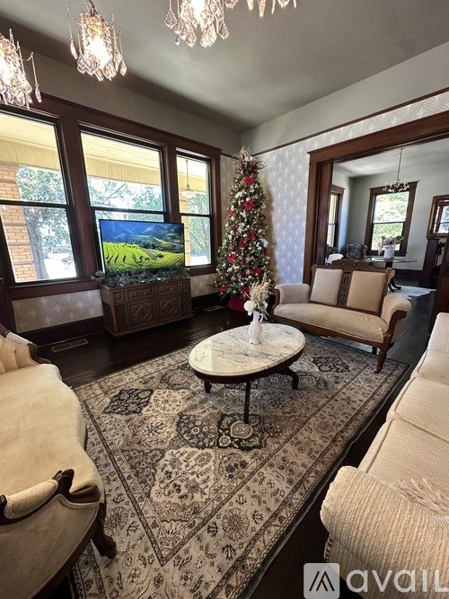 A living room with a Christmas tree and a rug.